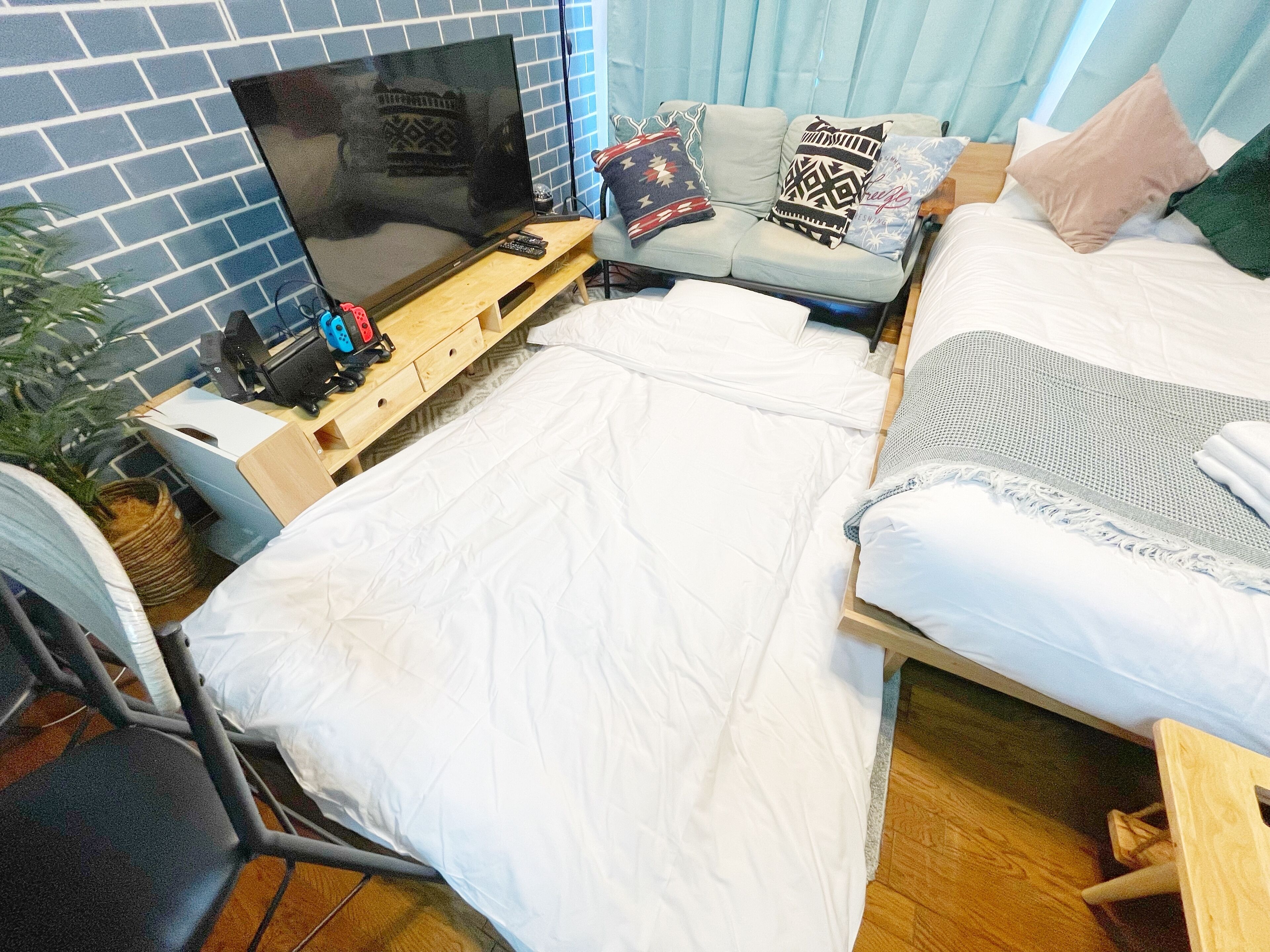 A compact hotel room with a bed, a sofa, a TV, and a desk.