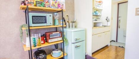 Una cocina compacta con microondas, tostadora y refrigerador antiguo.