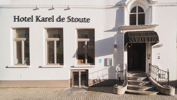 Hotel Karel de Stoute con una fachada clásica, ventanas amplias y una entrada acogedora con escalones y un porche cubierto.