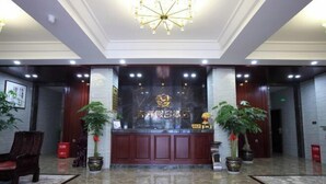 A hotel lobby with a reception desk, potted plants, and a chandelier. - Youth Holiday Hotel (Fuding)