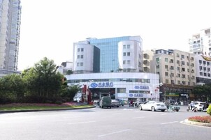 Un edificio de varios pisos con diseño moderno, que presenta fachada de vidrio y planta baja comercial.