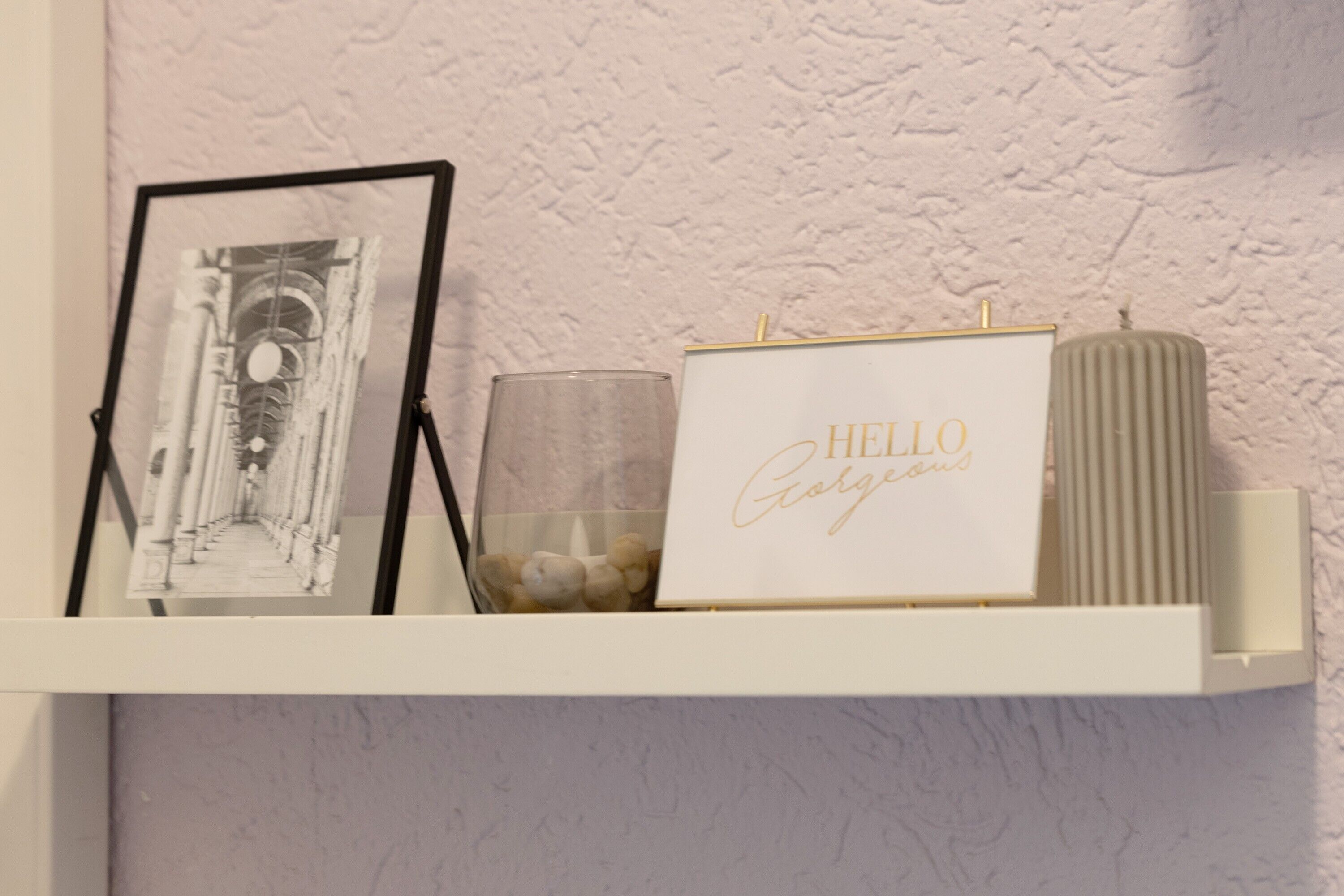A shelf with a framed black and white photo, a candle, and a card with 'HELLO Georgina' written on it.