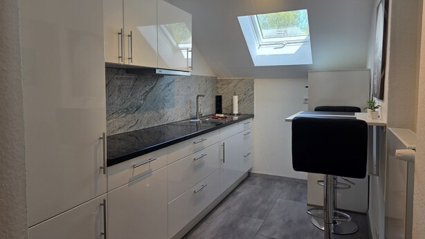 A modern kitchen with white cabinets, a black countertop, and a skylight. - Apartment 'Tifra-living' with Wi-Fi (Velbert-Neviges)