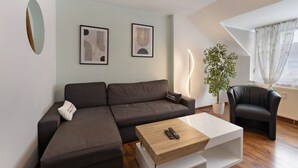 A modern living room with a sectional sofa, a coffee table, a black armchair, and two abstract wall art pieces. - Apartment 'Tifra-living' with Wi-Fi (Velbert-Neviges)