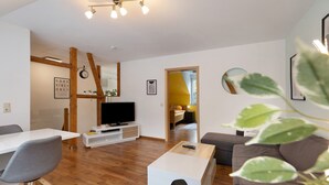A modern living room with a flat-screen TV, a coffee table, and a sofa. - Apartment 'Tifra-living' with Wi-Fi (Velbert-Neviges)