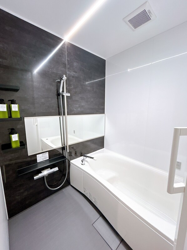 Une salle de bain moderne dotée d’une grande baignoire, d’une douche et d’un meuble-lavabo avec un miroir.