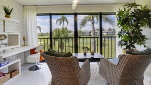 A balcony with wicker chairs, a table, and a ceiling fan. - Beach Life 7622 (Fort Pierce)