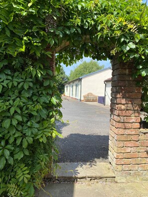 Enter a serene garden setting through this charming entrance, surrounded by lush greenery and a beautifully maintained courtyard.