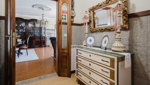 Une pièce dotée d’une porte en bois, d’un coin repas agrémenté d’un lustre, d’un miroir mural et d’une commode ornée d’assiettes décoratives.