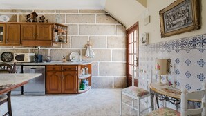 Une cuisine avec des meubles de rangement en bois, une table à manger et une chaise.