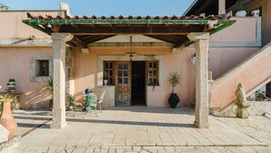Un patio abrité avec un toit en tuiles, un banc en pierre et des plantes en pot.