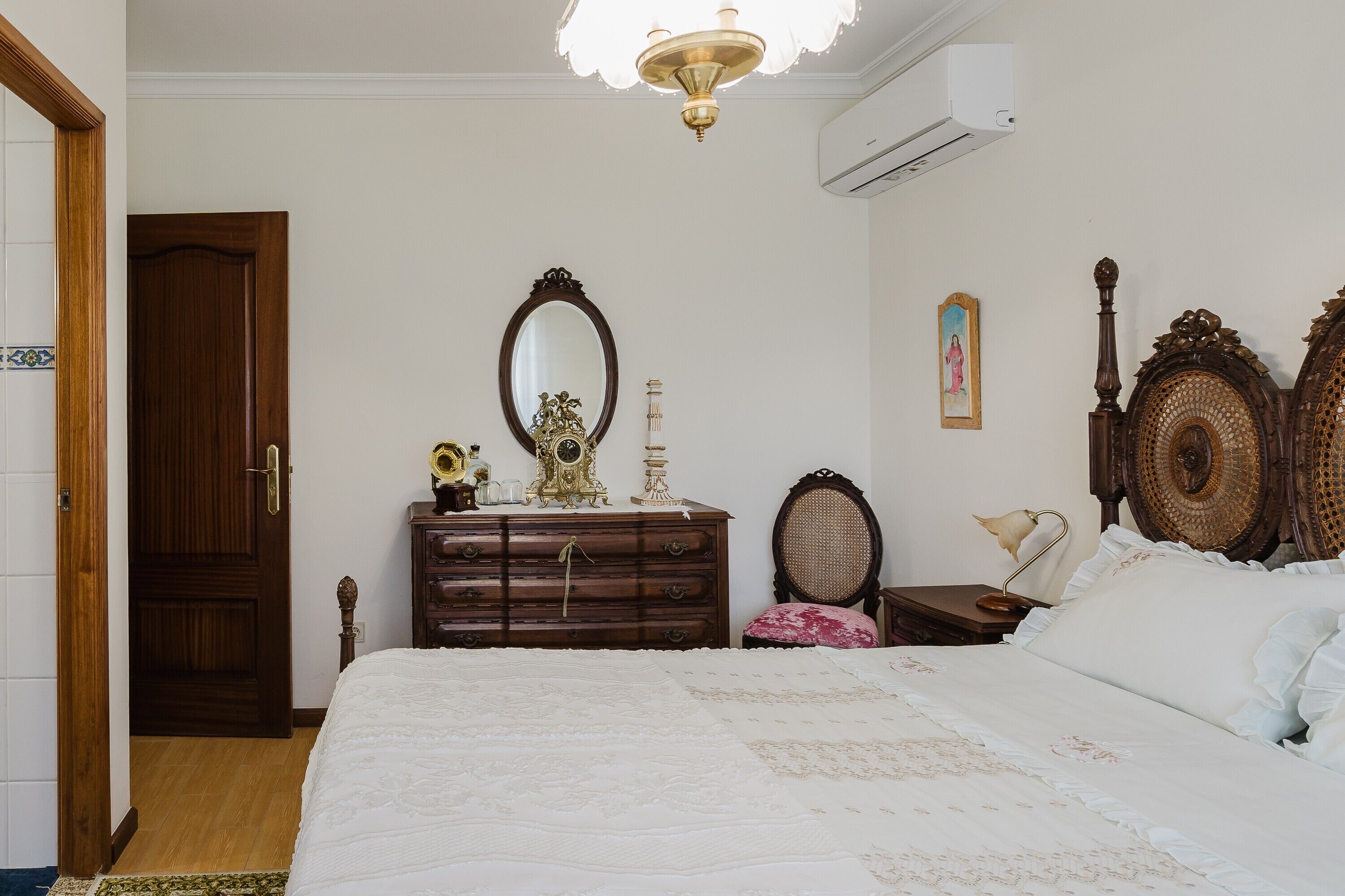 A bedroom with a bed, dresser, mirror, and a wooden headboard.