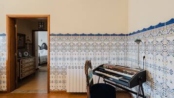 A room with a piano, a chair, and a radiator.