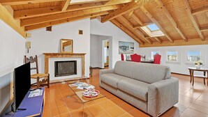 A spacious living room with a high ceiling, a fireplace, a sofa, and a television. - Attico a Caslano near to Golf Club Lugano, Caslano, Switzerland (Caslano)