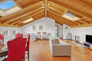 A spacious loft with high ceilings, wooden beams, and skylights.