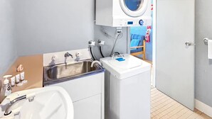 Ein kleines Badezimmer mit Waschbecken, Waschmaschine und Handtuchhalter.
