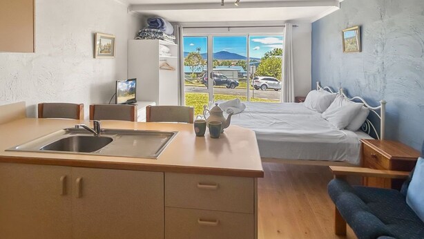 Ein kleines Zimmer mit Küchenzeile, einem Bett und einer Sitzecke.