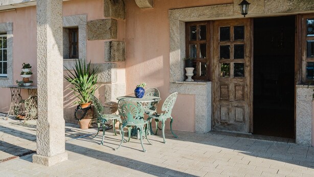 Eine Terrasse mit Tisch und Stühlen, einem Blumentopf und einer Holztür.