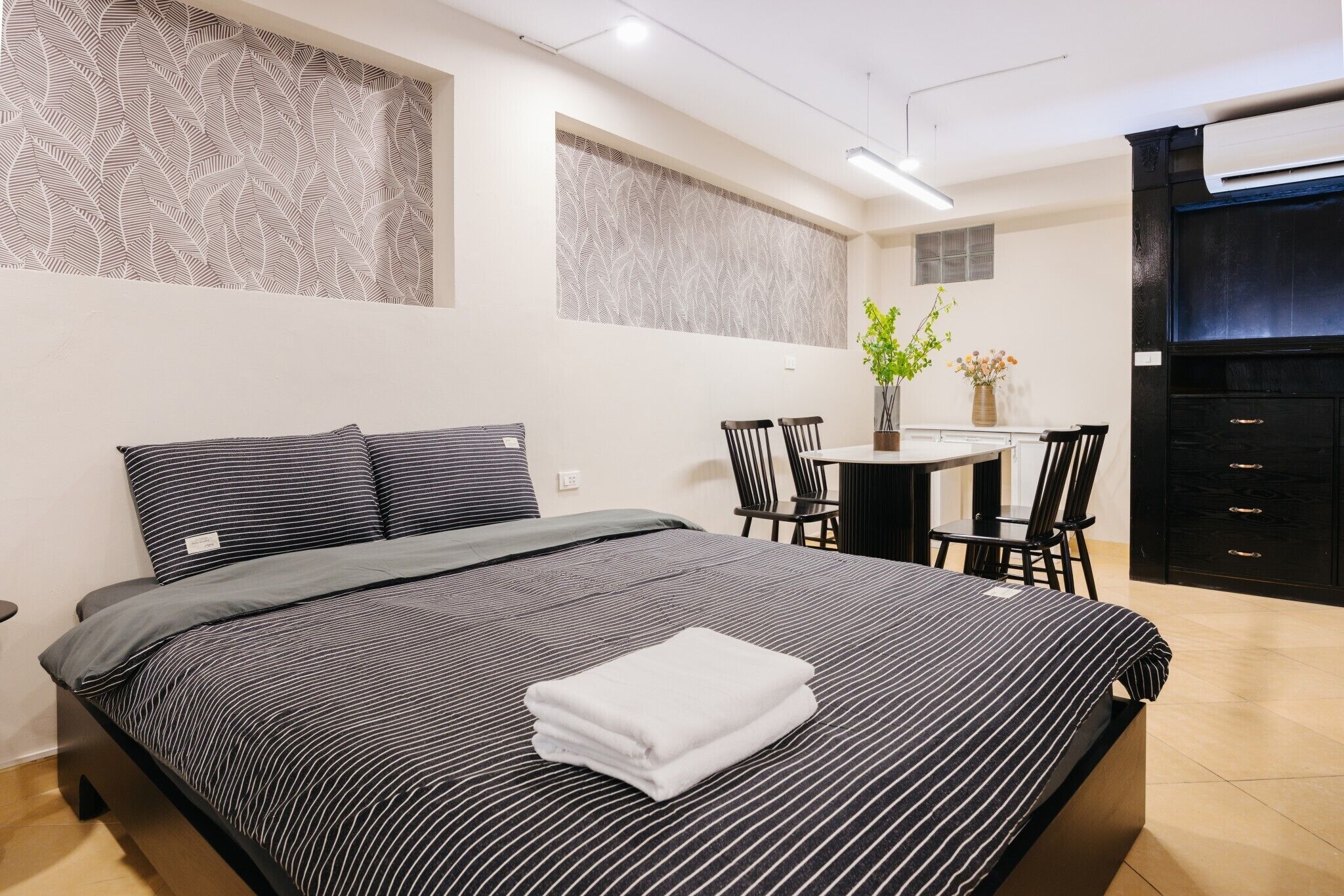 Una habitación de hotel moderna con una cama grande, un escritorio pequeño y una silla.