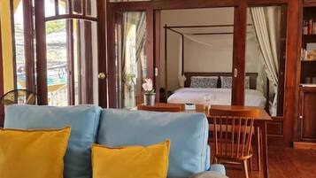 A room with a blue sofa, a wooden dining table, and a bed with a canopy.