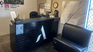 A reception desk with a large 'A' logo, a clock, and a calendar on the wall. - Aquarious motor inn (Hamilton)
