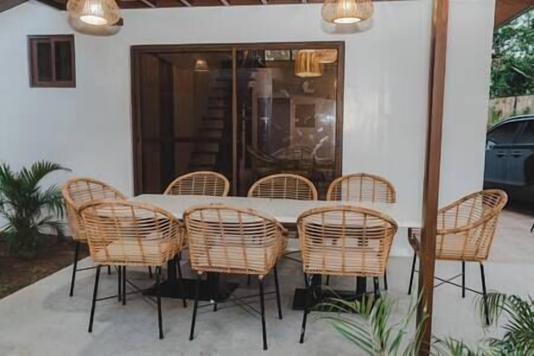 A dining area with a white table and six wicker chairs.