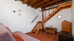 A room with a wooden staircase, a sofa, a wooden cabinet, and a small table with a vase. - Holiday Home 'Mary Valverde' with Sea View, Private Terrace and Wi-Fi (Villa de Valverde)