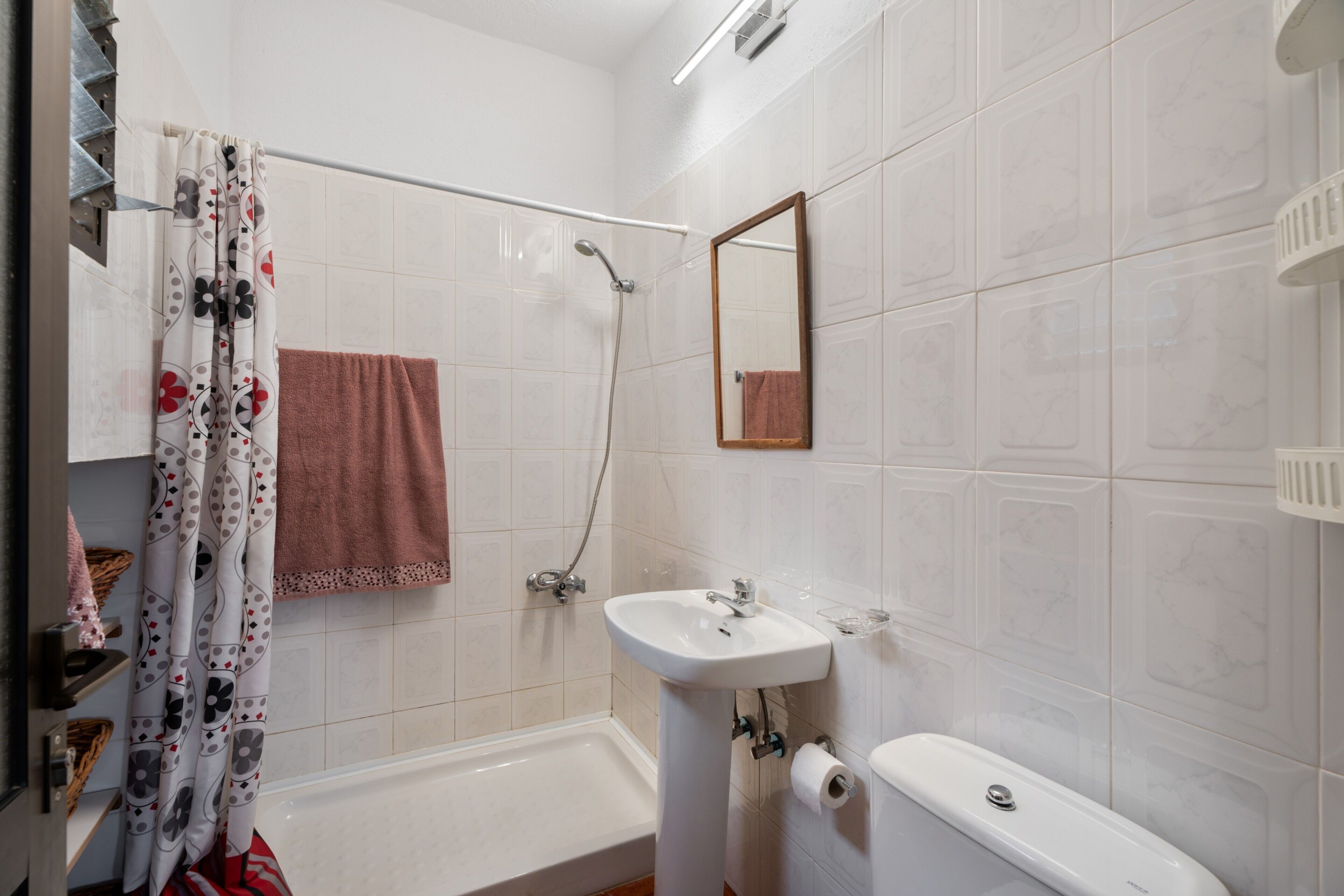 A bathroom with a bathtub, a sink, a shower, a mirror, and a towel rack.
