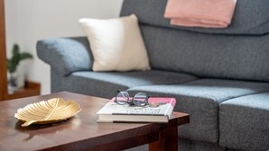 A sofa with a blanket, a cushion, and a pair of glasses on a book. - Holiday Home 'Mary Valverde' with Sea View, Private Terrace and Wi-Fi (Villa de Valverde)