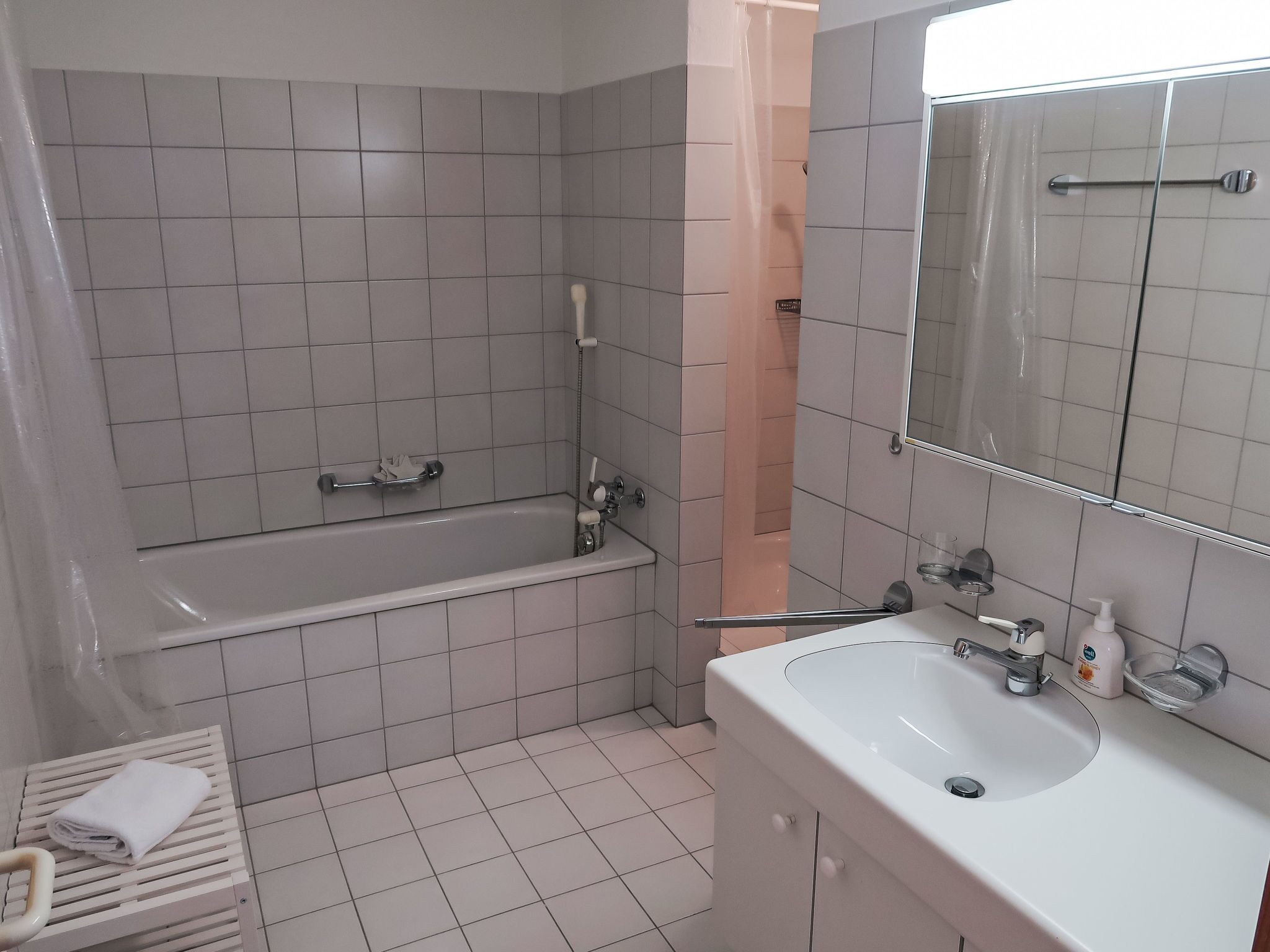 Een badkamer met een bad, wastafel en spiegel.