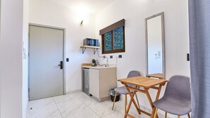 A compact kitchen with a refrigerator, microwave, and sink, a small dining table with two chairs, and a window with a view. - Cozy 1-bedroom apartment with WiFi, AC in fantastic San José (San José)