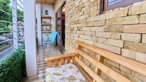 A wooden bench with a floral cushion outside a building with stone walls and a wooden ceiling. - Cozy 1-bedroom apartment with WiFi, AC in fantastic San José (San José)