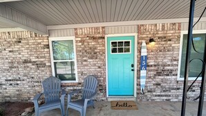 A house with a turquoise door, two plastic Adirondack chairs, a doormat with "hello" on it, and a surfboard with the number 156 on the wall. - Charming 3-bedroom house in beautiful Kaw City just minutes from Kaw Lake. (Kaw City)
