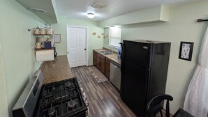 A compact kitchen with a stove, refrigerator, and wooden cabinets. - Charming 3-bedroom house in beautiful Kaw City just minutes from Kaw Lake. (Kaw City)