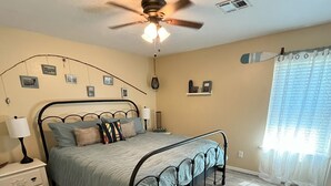 A bedroom with a bed, bedside table, lamp, ceiling fan, and a window with curtains. - Charming 3-bedroom house in beautiful Kaw City just minutes from Kaw Lake. (Kaw City)
