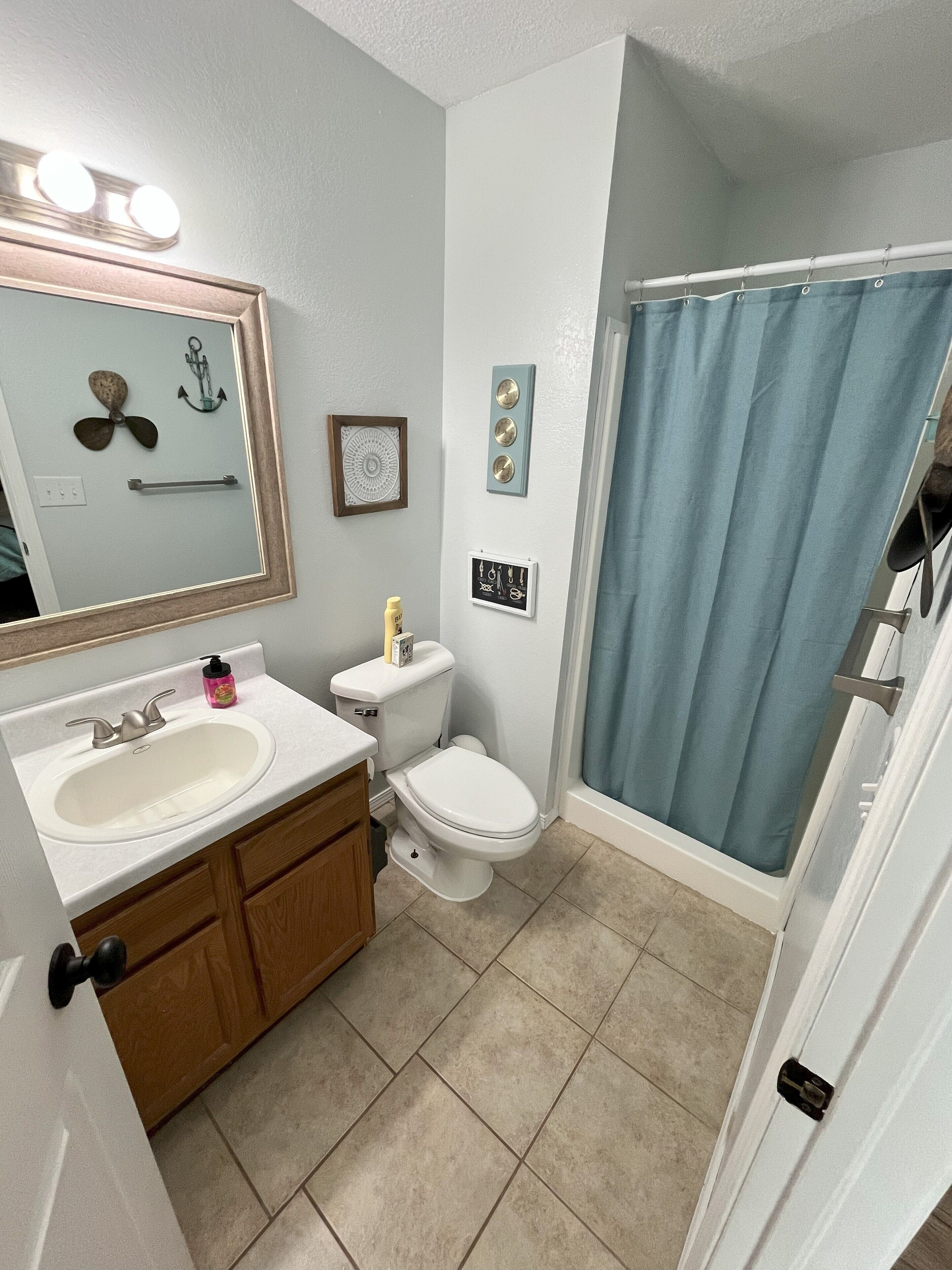 Une salle de bain avec un lavabo, des toilettes et un rideau de douche.
