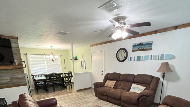 A living room with a brown leather sofa, a dining area with a table and chairs, and a ceiling fan. - Charming 3-bedroom house in beautiful Kaw City just minutes from Kaw Lake. (Kaw City)