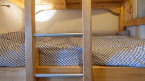 A bunk bed with a wooden frame and patterned bedding. - Chalet 'Face Au Mont Blanc, South Facing' with Mountain View, Private Terrace & Wi-Fi (Cordon)