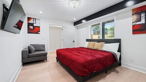 Ein modernes Schlafzimmer mit einem Bett, einem Sofa und Kunstwerken an den Wänden.
