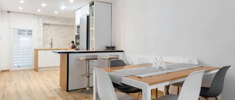 Una cocina moderna con armarios blancos, un salpicadero de mármol y un horno empotrado.
