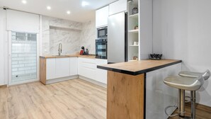 A modern kitchen with white cabinets, a wooden countertop, and a built-in oven.
