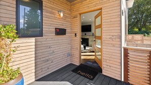 A wooden exterior with a sliding glass door, a black mailbox, and a welcome mat. - Luxury 3 Bed/3 Bath NEW Home in Ruston (Tacoma)