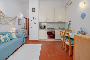 A compact living space with a kitchenette, a dining area, and a bedroom.