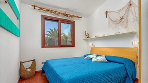 Une chambre à coucher avec un lit, une fenêtre, une étagère ornée d’objets décoratifs et un panier en osier.