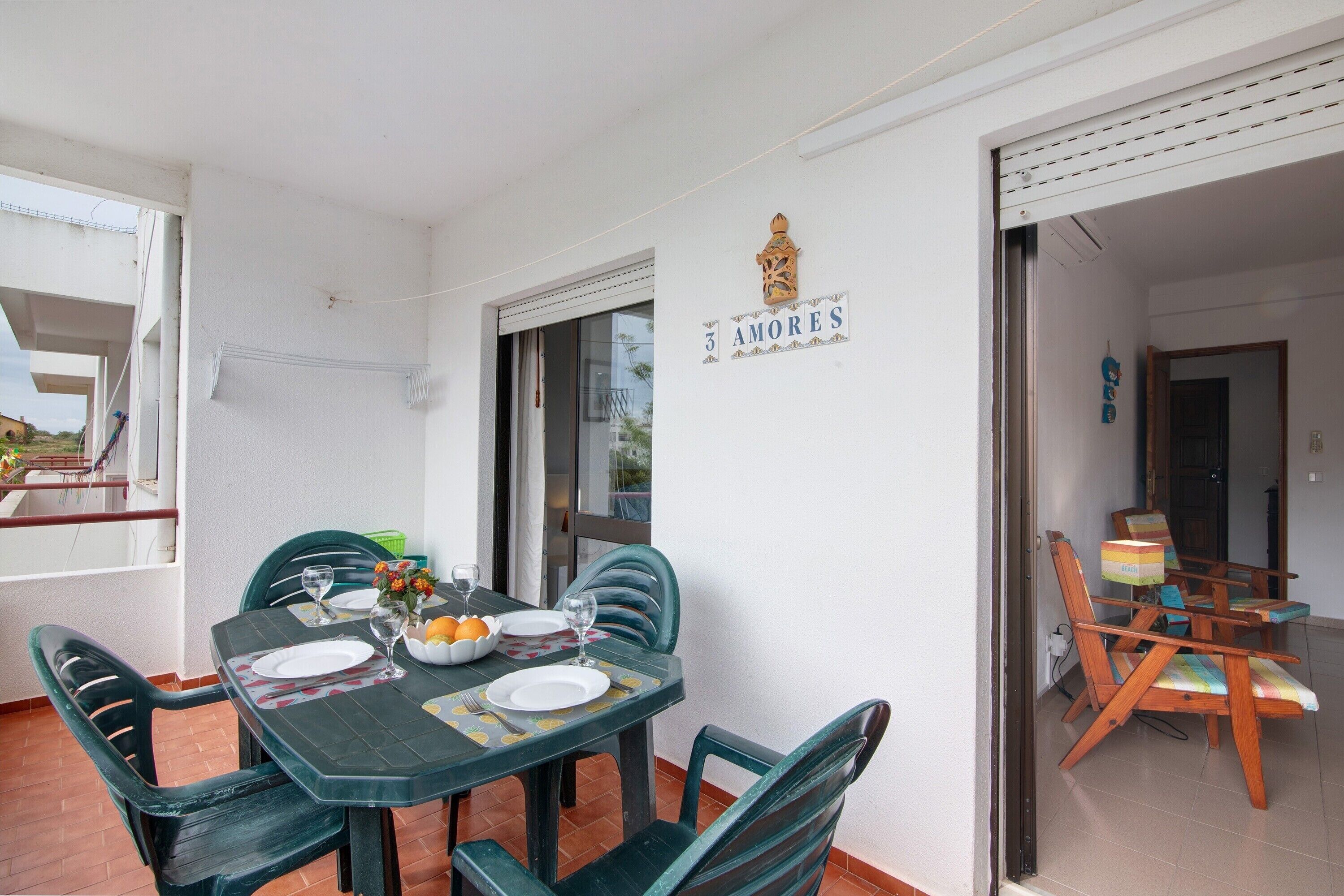 Comedor con una mesa dispuesta para cuatro, sillas, un letrero en la pared y vistas al exterior.