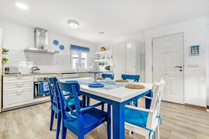 Une cuisine moderne avec des meubles blancs, des chaises bleues et une table à manger pour quatre personnes.