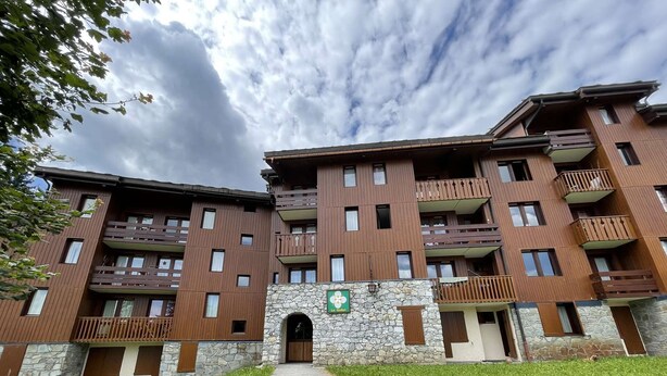 Un hotel de diverses plantes amb façana de pedra, balcons i una entrada central.