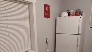 Una cocina compacta con horno integrado, un refrigerador blanco y una ventana con persianas.