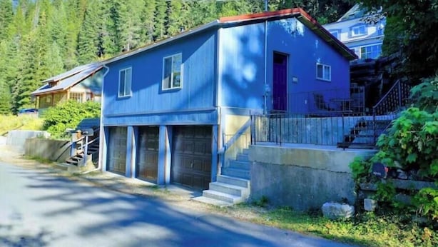 Una casa de dos pisos con techo rojo, un garaje delantero y una escalera que lleva a la entrada.