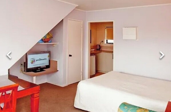 Una camera d'albergo con un letto, una scrivania con un computer e angolo cottura.